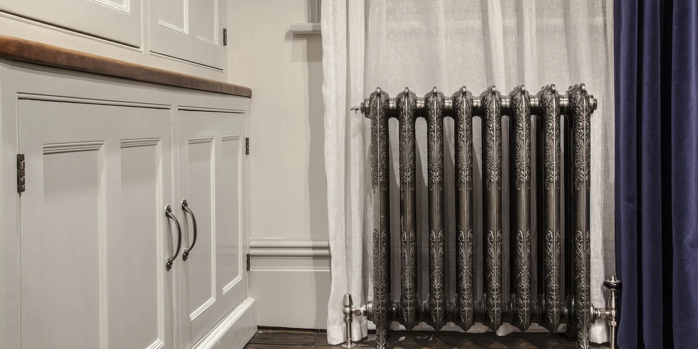 Cast iron radiator in a hand-polished finish in a panelled dressing room