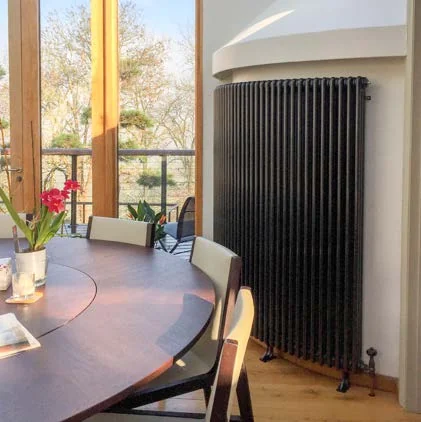 Curved Castrads Florence steel column radiator following the wall of a bay window in a dining room