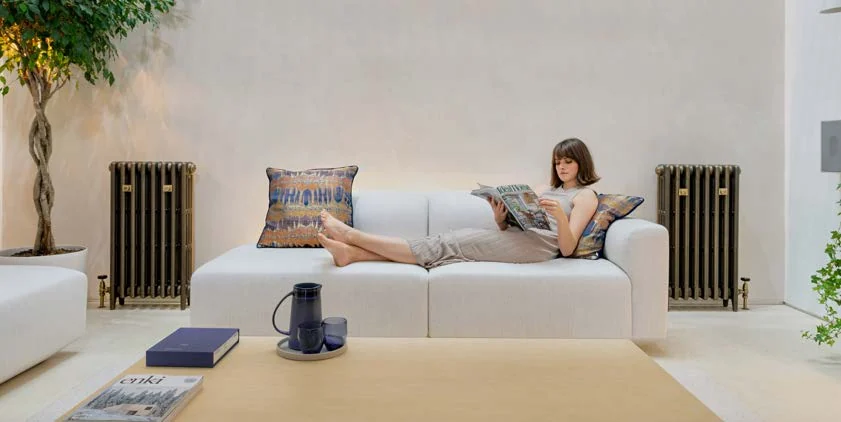 Castrads Mercury cast iron column radiators either side of a sofa in a pale modern living room