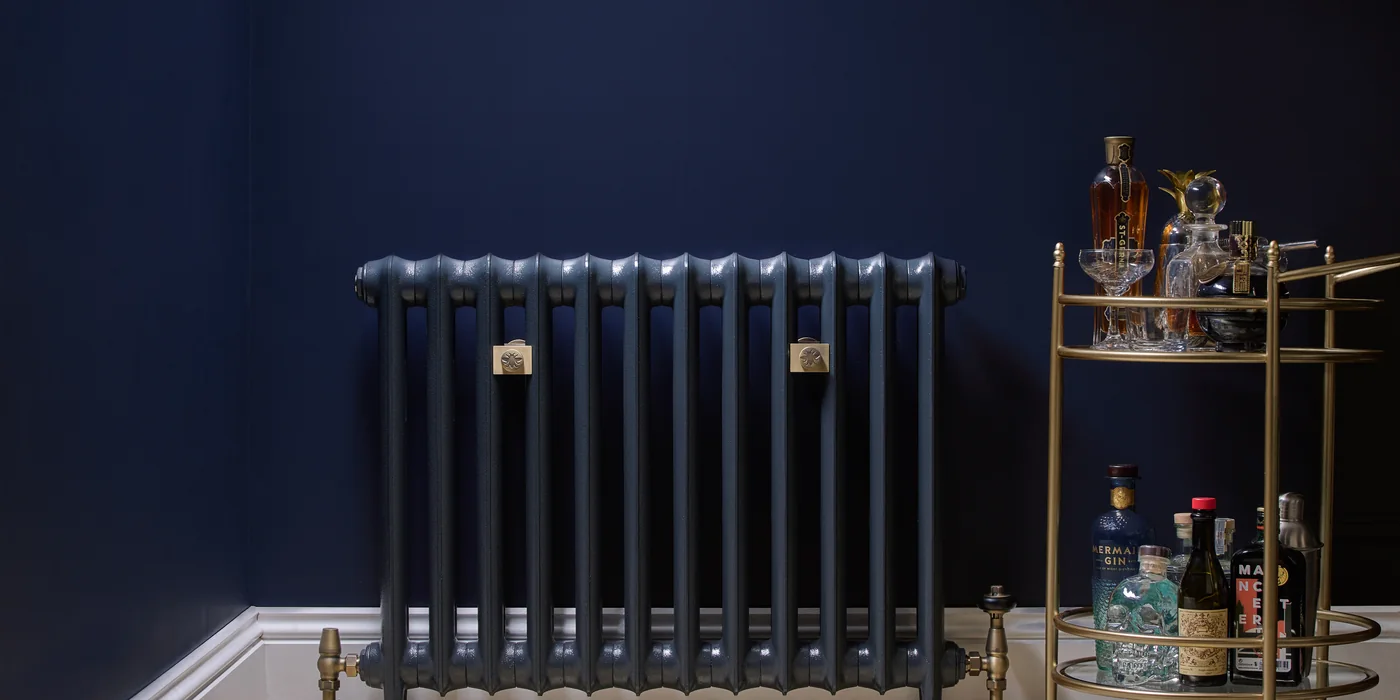 Castrads Emmeline I 665 mm cast iron radiator in Midnight Ink against a navy wall