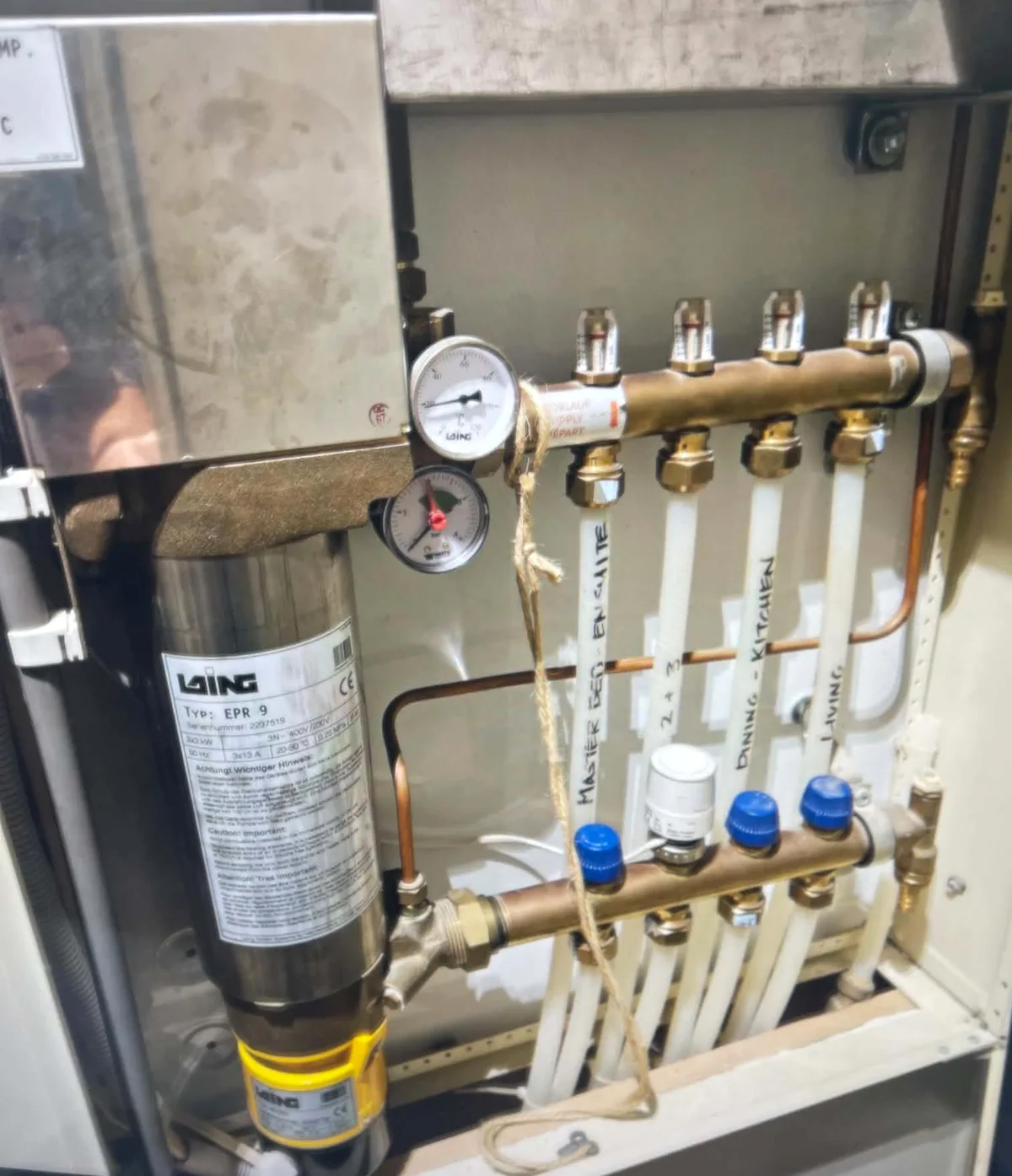 Laing EPR 9 electric boiler beside an underfloor heating manifold in a wall cabinet