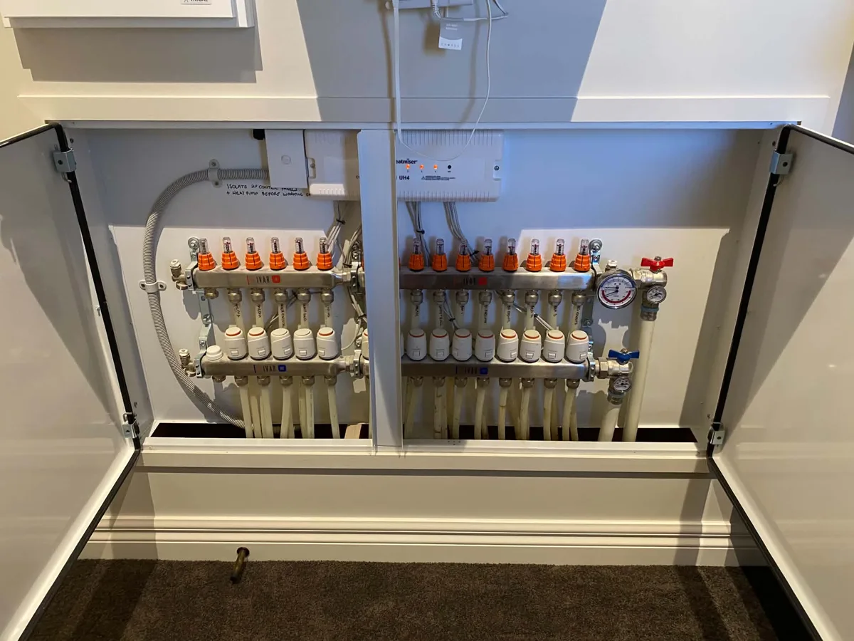 Two underfloor heating manifolds with a flow gauge and zone valve on every circuit, recessed in a wall cabinet