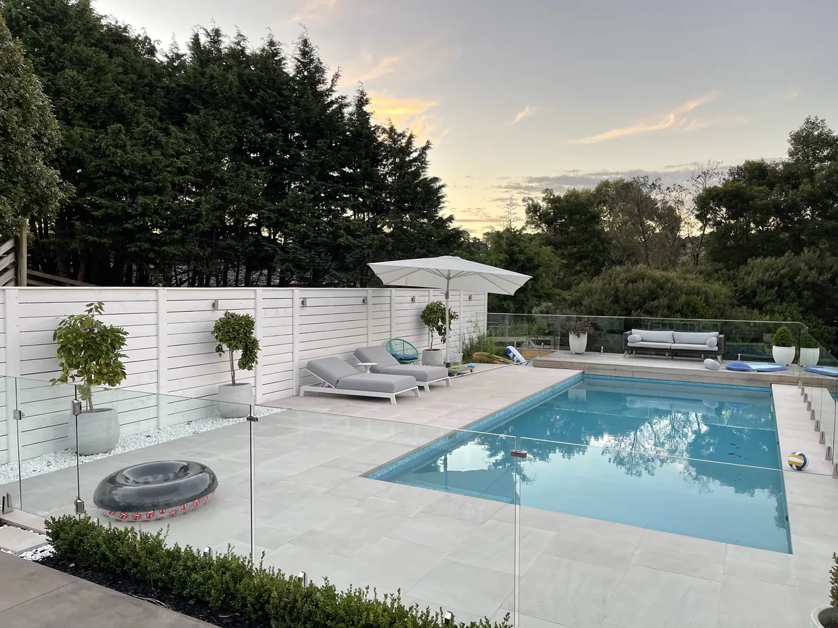 A heated swimming pool in an Auckland garden at dusk, still warm enough to swim