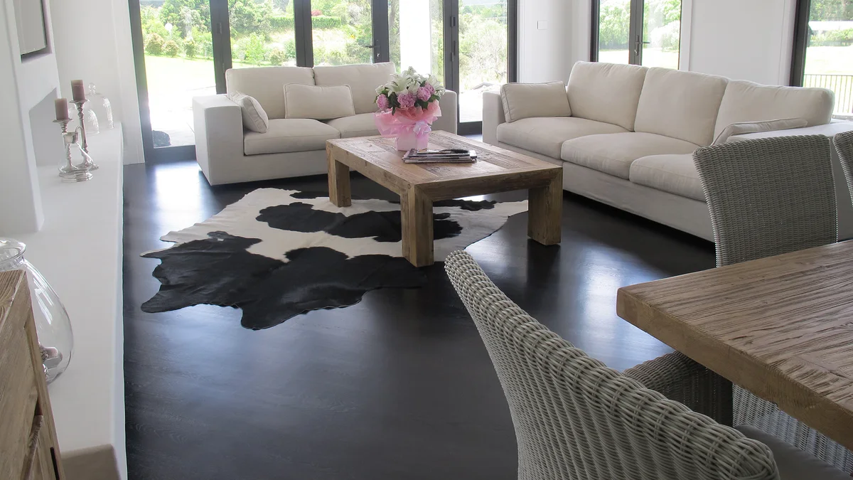 Living room with dark timber floor, cream sofas and bi-fold doors to the garden