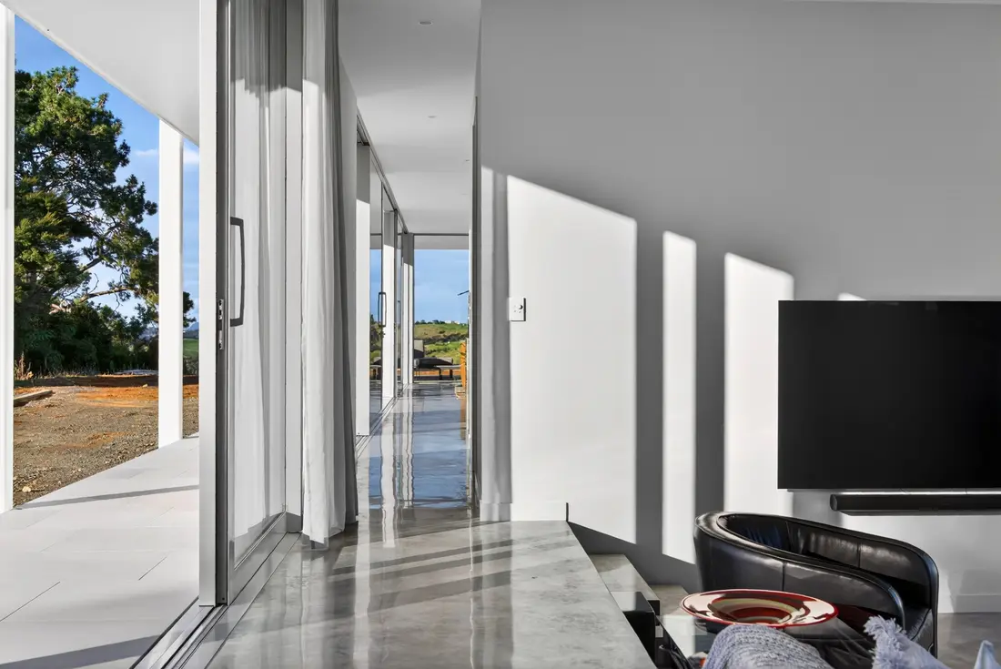 Gallery hallway with the concrete floor continuing out through sliding doors to the terrace